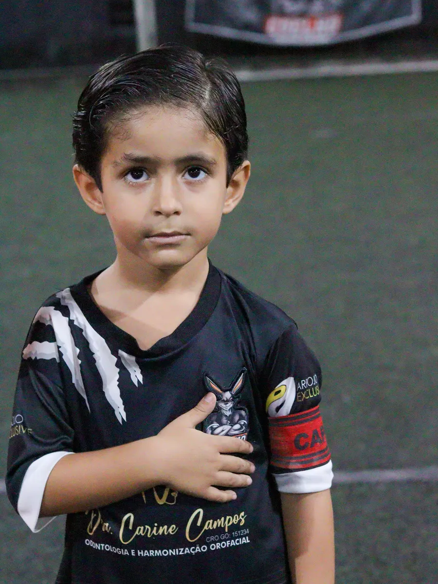 Aluno do Coelho com a mão no peito, de uniforme preto com as garras brancas